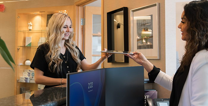 Handing tablet to dental team member over a desk