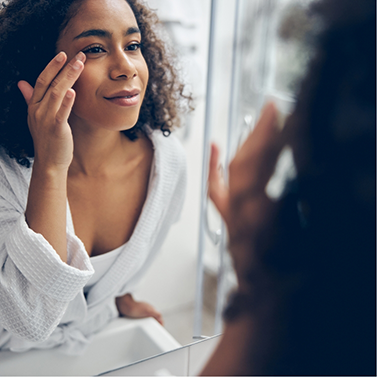 Woman leaning forward and looking at face in mirror