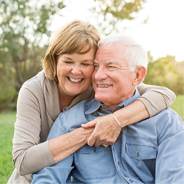 Senior woman hugging senior man from behind