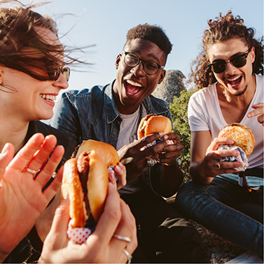 Several people eating sandwiches outside