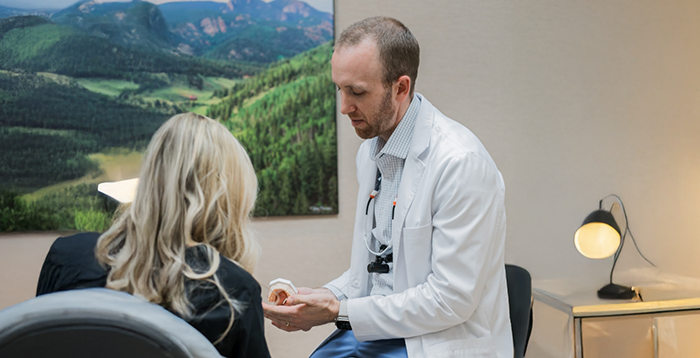 Dentist sitting and showing patient model of teeth