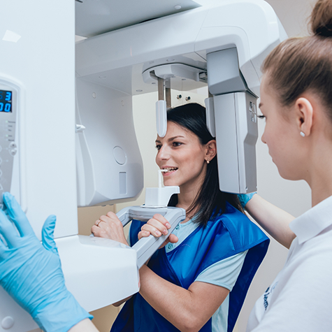 Woman about to have cone beam X ray taken by female dental team member