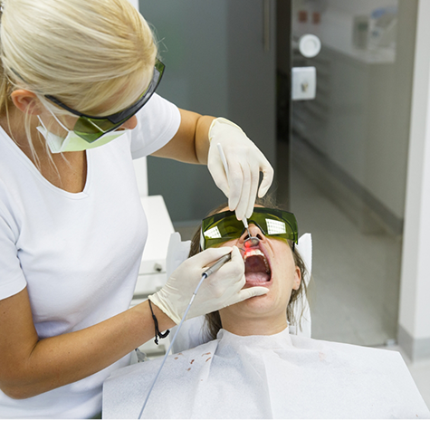 Blonde dentist performing treatment with soft tissue laser