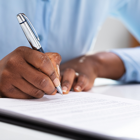 Close-up of man writing on form with pen