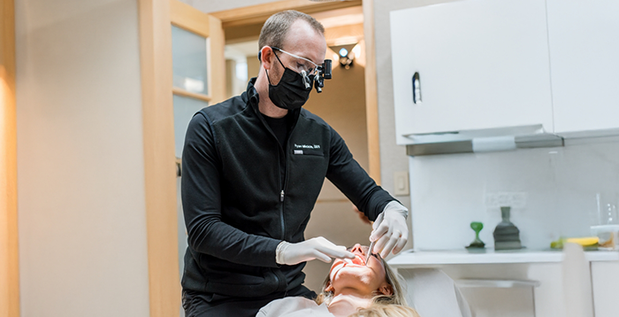 Dentist with magnifying glasses treating a patient