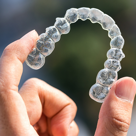 Close-up of hand holding an Invisalign clear aligner in Greenwood Village