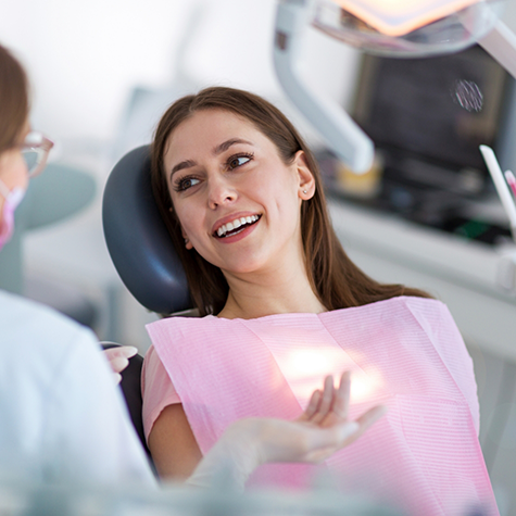 Woman in dental chair smiling and looking at dentist