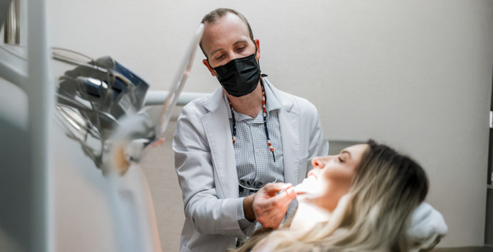 Dentist with mask shining light on patient's teeth