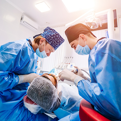 Two dentists with masks treating a dental patient