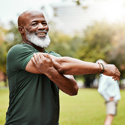 Bearded man standing outside smiling and stretching