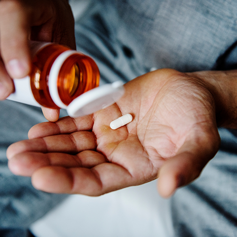 Close-up of hands holding bottle and pill